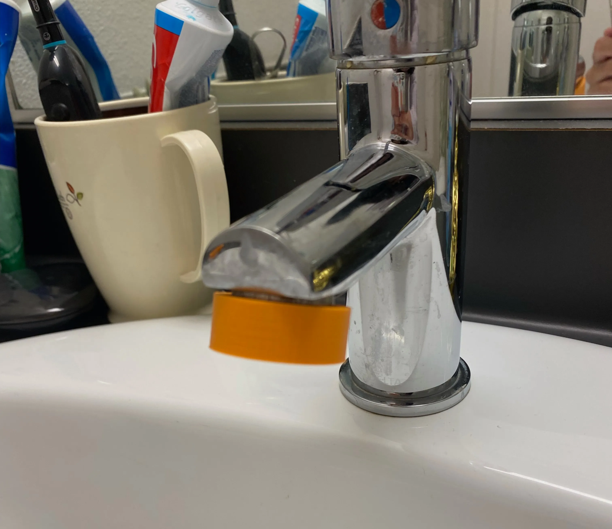 Orange 3D-printed Glow Tap fitted on a bathroom faucet aerator